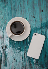 Cup of cofee and phone on tiffany wood background