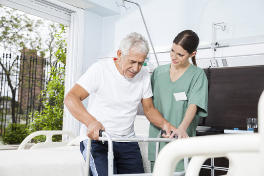 Young Nurse Helping Patient In Using Walker At Nursing Home