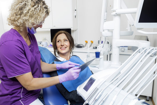 Assistant Showing Report To Smiling Patient On Tablet Computer