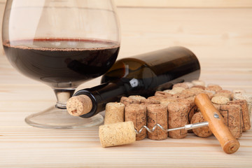 Corkscrew, corks, bottle of wine and a glass. Selective focus