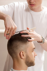 Obraz na płótnie Canvas barber cuts hair with scissors