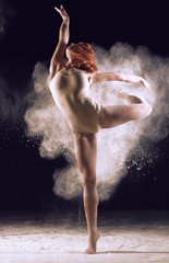 Dancer performing over black background with powder burst to show power and movement. Dancer performing over black background with powder.
