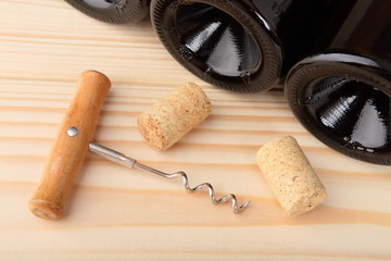 Corkscrew, corks and bottles of wine. Close-up. Selective focus