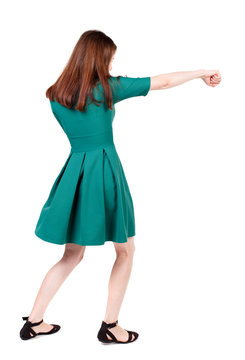 skinny woman funny fights waving his arms and legs. Isolated over white background. The slender brunette in a green short dress has outstretched arm.