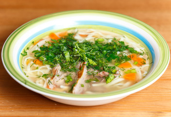 Chicken soup with noodles and vegetables in ceramic bowl