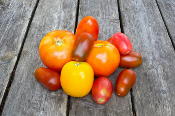 A duferent colored tomatoes on the wooden deck