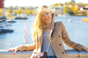 Wind blows hair on the face of smiling blonde while she poses on