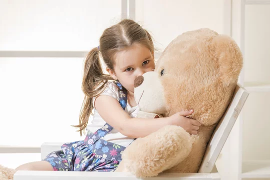 Portrait of expressive little girl hugging and kissing huge plush bear,  indoor shot on white room. Little girl playing with teddy bear Stock-Foto |  Adobe Stock