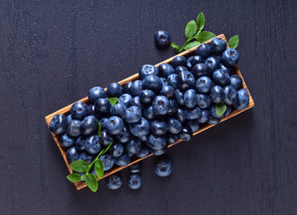blueberries with green leaves in wooden dish