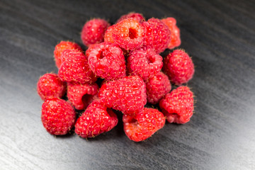 Raspberries isolated on black wooden background, selective focus, depth of field