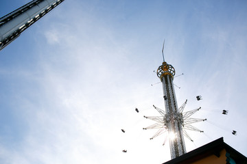 Carousel whirls people in tha air under the blue sky