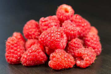 Raspberries isolated on black wooden background, selective focus, depth of field