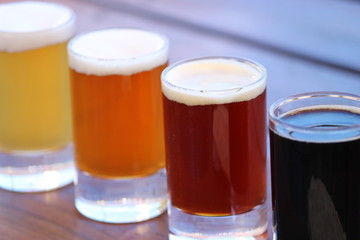 Four different varieties of craft beer on a wooden board and table