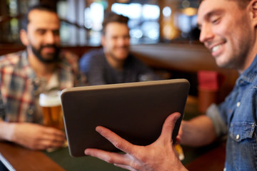 male friends with tablet pc drinking beer at bar