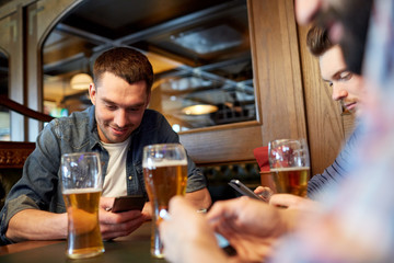 men with smartphones drinking beer at bar or pub