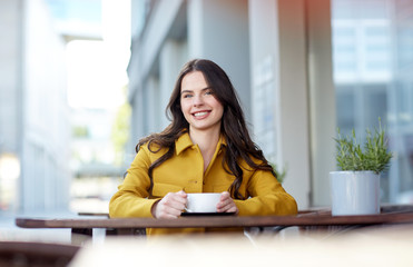 happy woman drinking cocoa at city street cafe