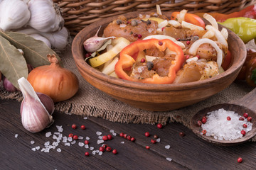 Marinated chicken in a clay bowl on old table.