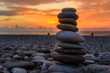 Pyramide de pierres sur le sable symbolisant le zen, l& 39 harmonie, l& 39 équilibre. Mer Noire au coucher du soleil en arrière-plan.