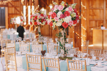 Gorgeous pink bouquet stands over the dinner table covered with