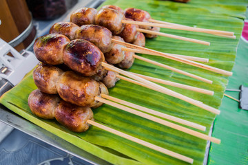 thai sausage with stick sale on banana leaf at the street market