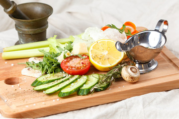 Fresh salad mix, sliced vegetables, olive oil and spices on wood