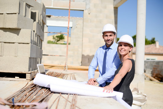 cute young woman architect with handsome foreman in building industry construction site