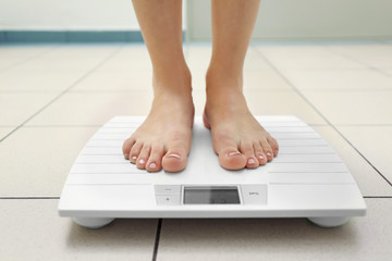 Female legs standing on floor scales