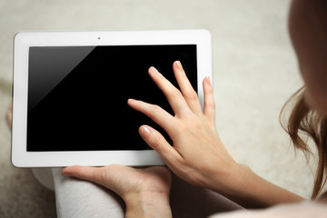 Woman holding tablet on blurred carpet background