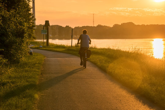Radfahrer bei Sonnenuntergang am Flussufer