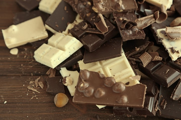 Chopped chocolate bars with nuts on wooden background