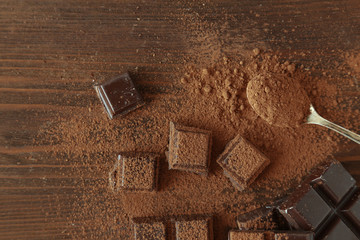 Chocolate pieces covered with cocoa powder on wooden background