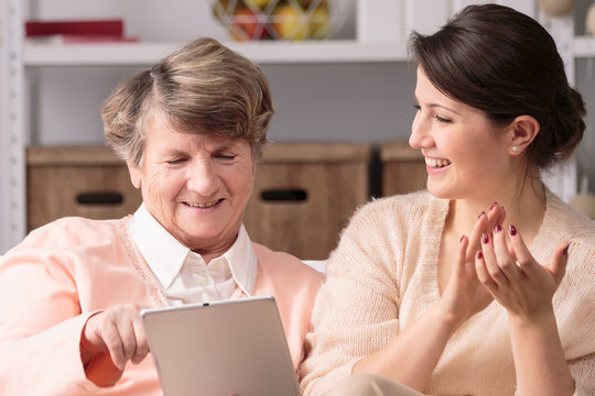 Elderly woman and female caregiver using tablet