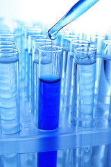 Close up of a pipette dropping a blue sample into a test tube