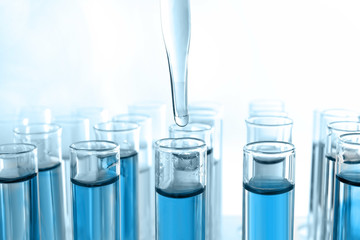 Close up of a pipette dropping a blue sample into a test tube