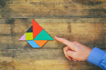 man's hand pointing at boat made from tangram puzzle