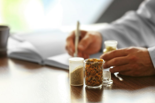 Bottles with dry inflorescence and doctor on background. Herbal medicine concept