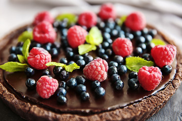 Delicious chocolate tart with berries on slate plate, closeup