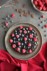 Delicious chocolate tart with berries on grey table, top view