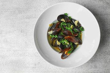 Plate with mussels with garlic and parsley on white wooden background