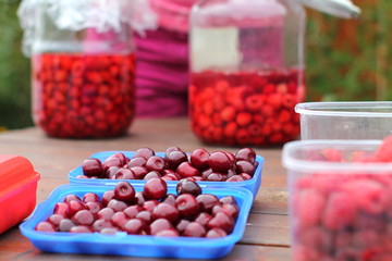Juicy ripe cherries in blue boxes and  two pots with raspberry compote  in background