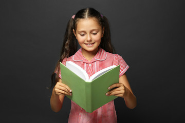 Cute girl reading book on grey background