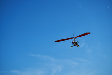 Fototapeta na wymiar Red motor hang glider flying in the blue sky.