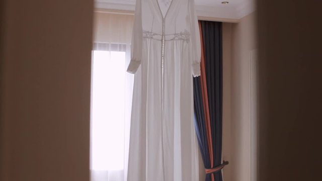 Chiffon wedding bridal dressing gown hanging on the hanger in the apartments