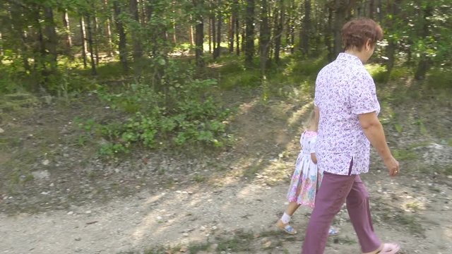 Grandmother granddaughter walk in the park outdoors. Walk through the forest.