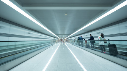 Perspective view of the airport tunnel. Light walkway equipped with flat escalators and people with...