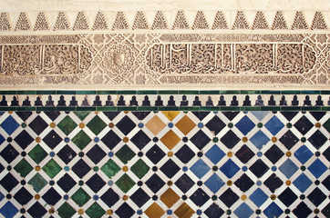 Moorish pattern from Alhambra, Granada, Spain - Closeup of a plaster wall with islamic motif and geometric tiles