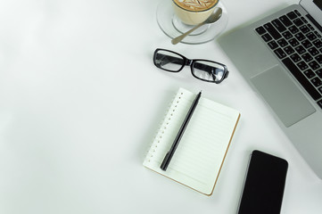 Office table with notepad, laptop and coffee cup.