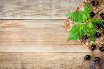 Fresh blackberries with leaves on wooden background in rustic style. Top view.