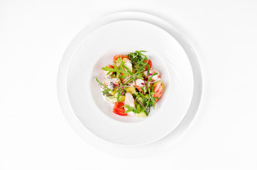 Salad with shrimp, tomatoes, cheese and rocket salad on a plate on a white background, top view