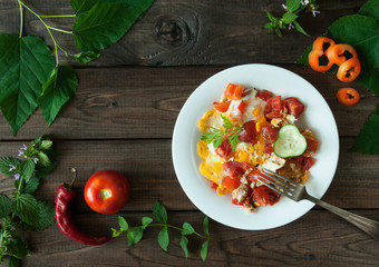scrambled eggs with vegetables on wooden background 